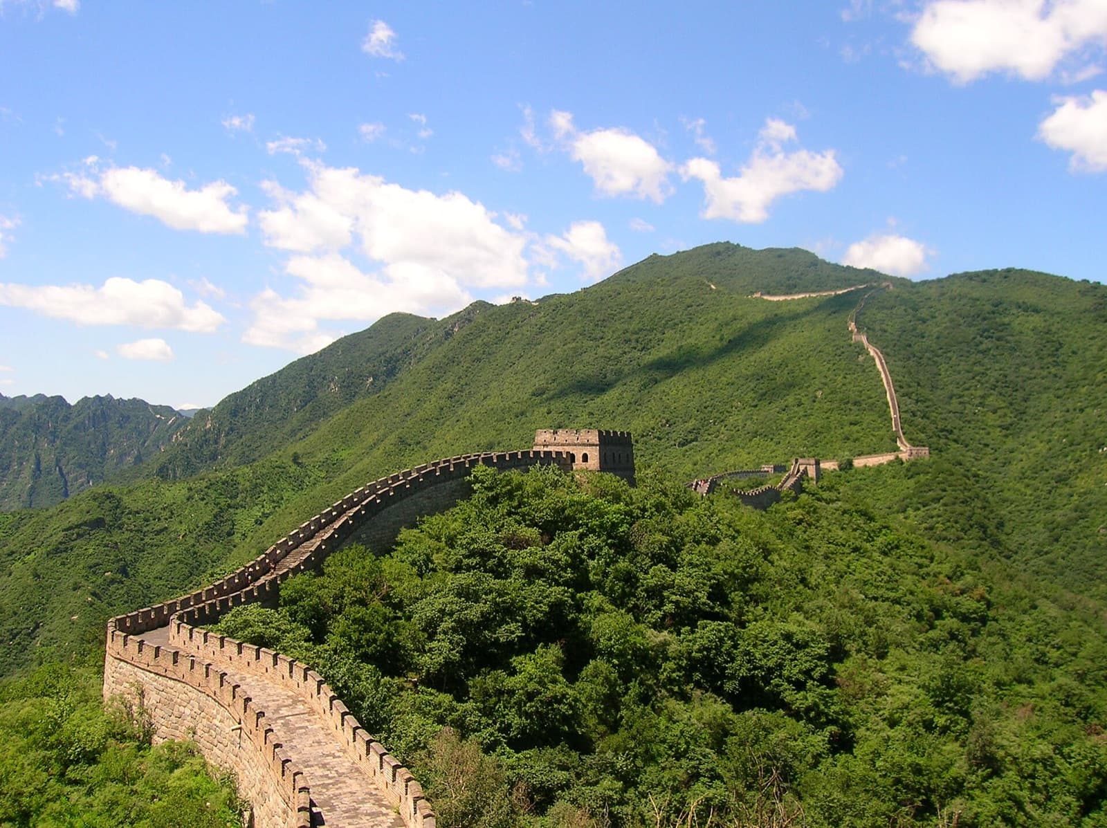 The Great Wall of China winding through green mountains